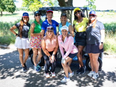 diverse ladies at a golf course standing in front of a golf cart