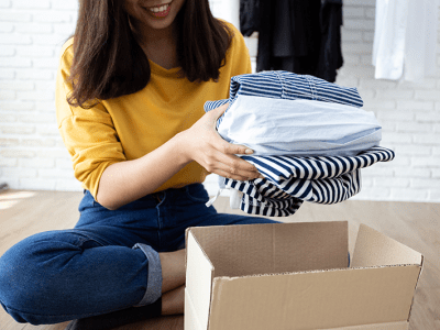 Woman holding Clothes with Donate Box In her room, Donation Concept.