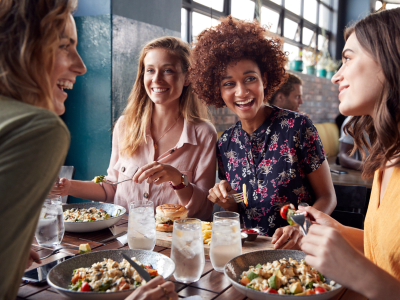 Four Young Female Friends Meeting For Drinks And Food Making A Toast In Restaurant
