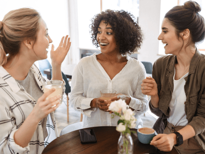 Happy young women friends having coffee break while relaxing at the cafe indoors
