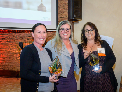 Three women smiling and holding awards