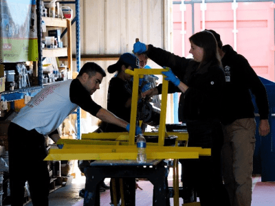 people gathered around table working in gloves painting a window frame