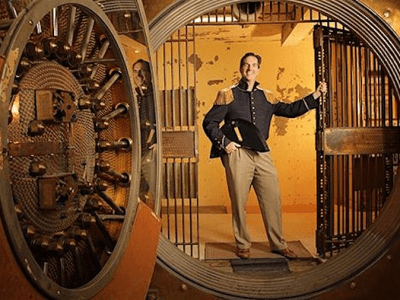 Man standing in a vault holding onto a barred gate
