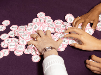 Diverse female hands reaching for pile of pink poker chips.