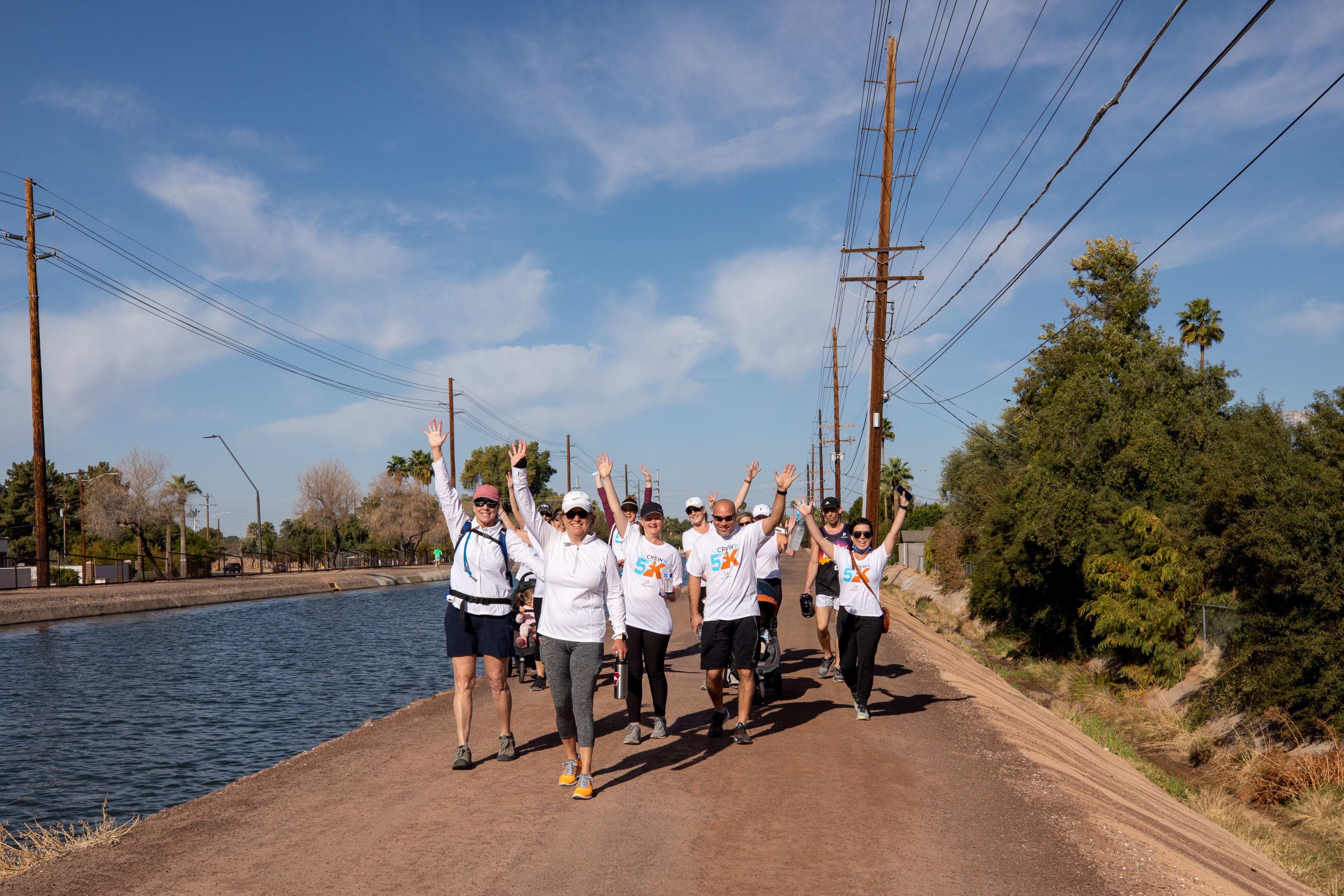 group exercising with arms in the air alongside river