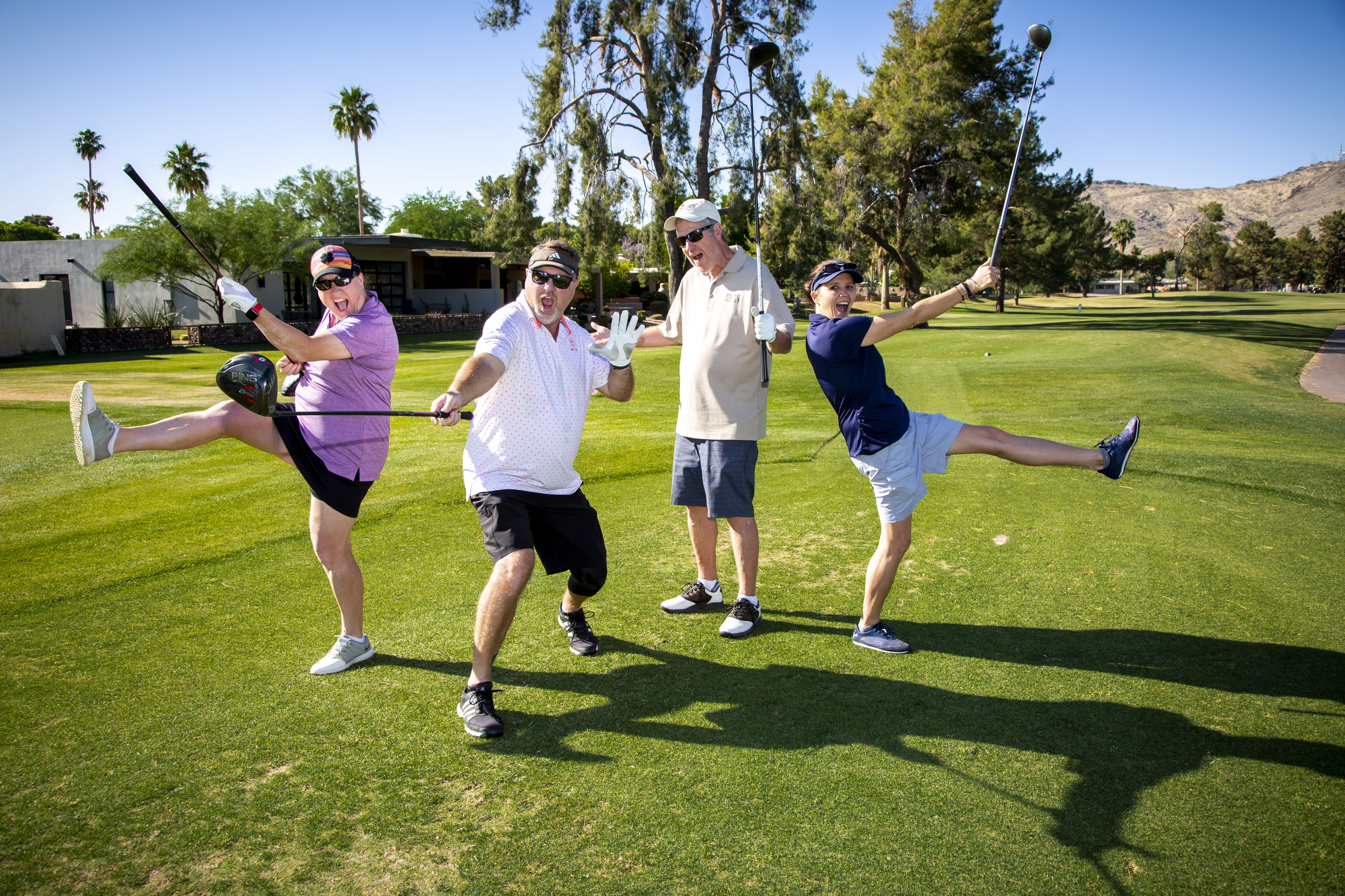 four golfers striking goofy poses on the green