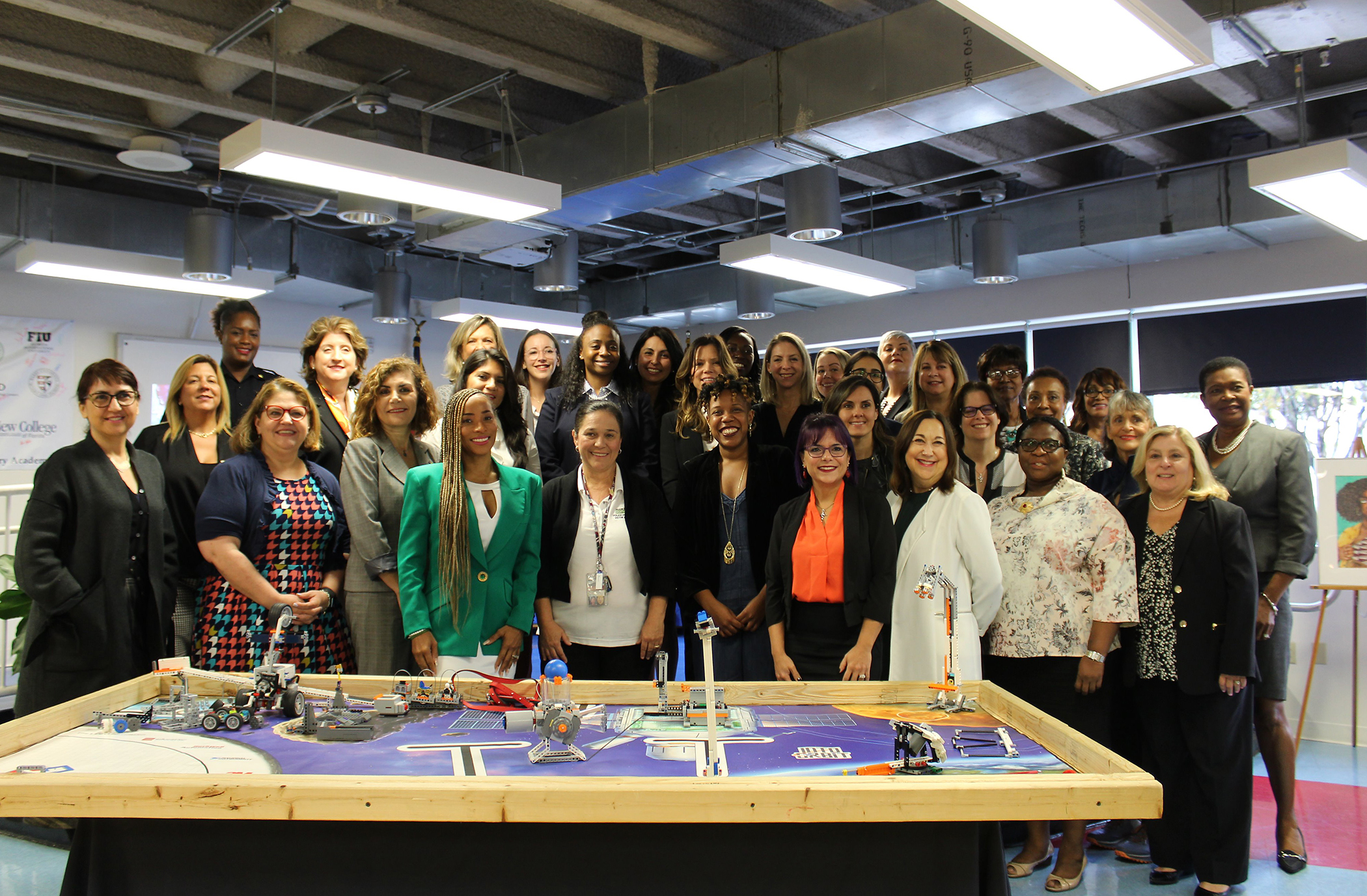 Group photo of college students and professionals over a worktable at a UCREW event