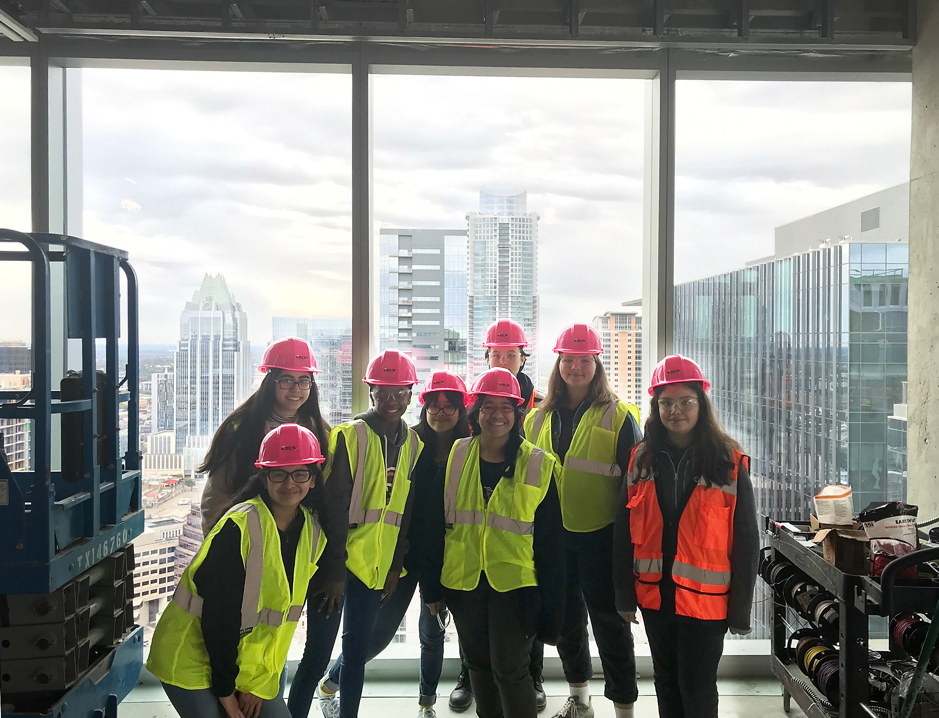 Several women in high-visibility jackets in a skyscraper work-site