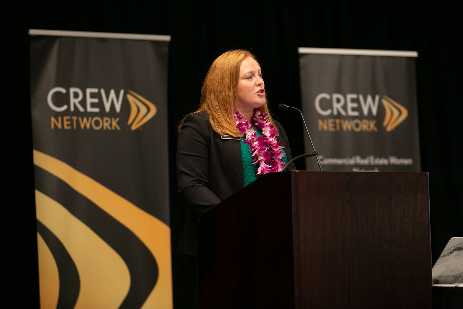 Woman at podium speaking at a CREW Network Convention