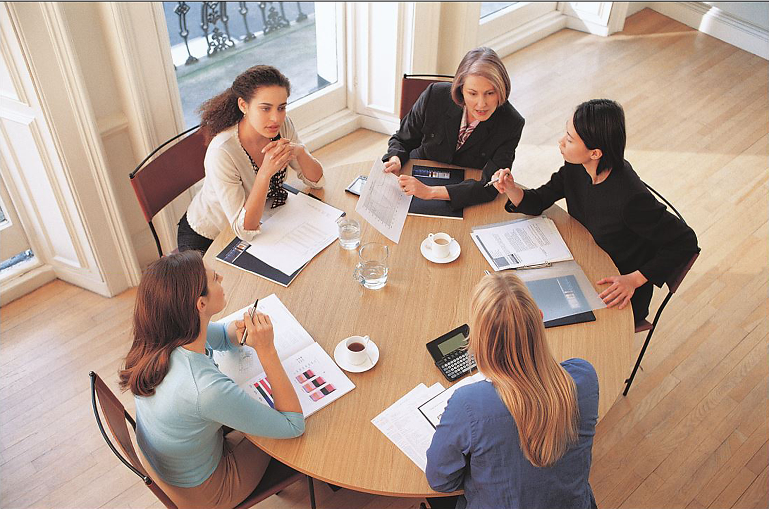 overhead view of businesswomen at a round table discussing documents