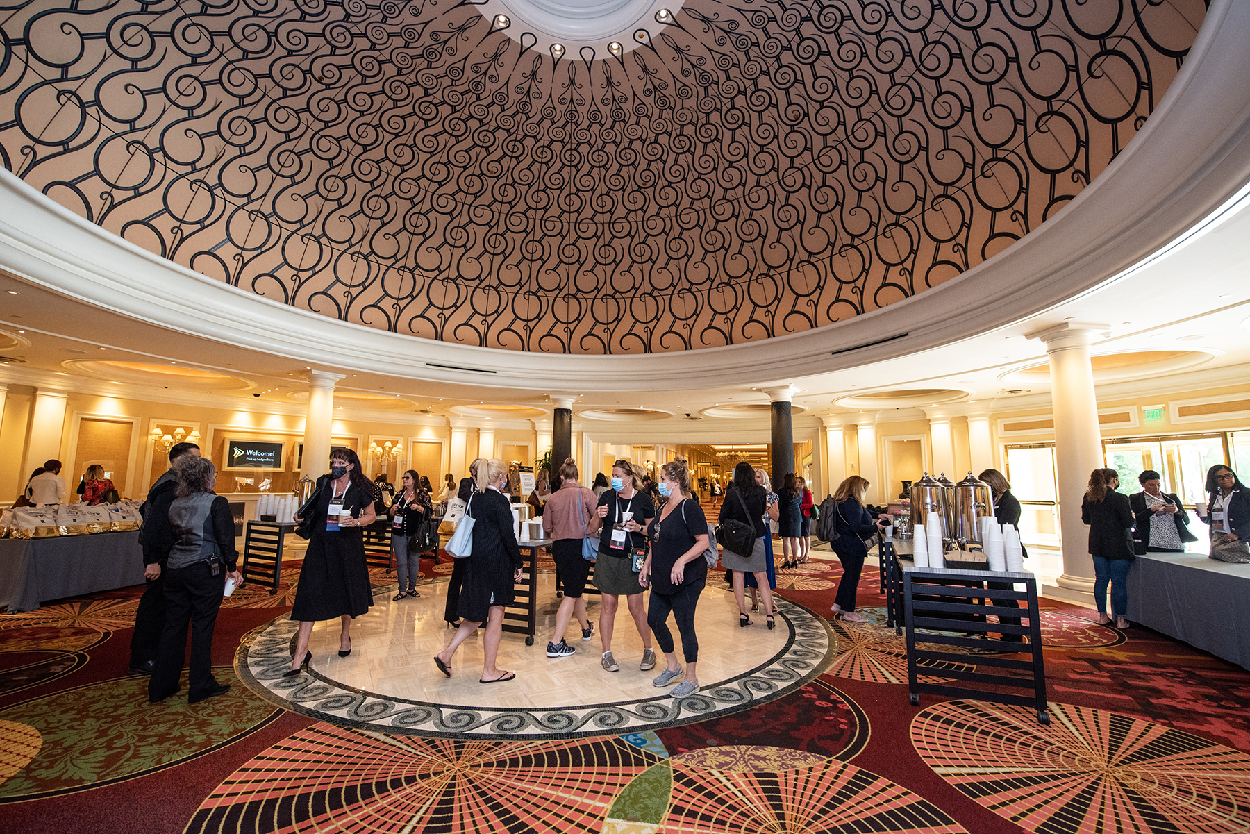 attendees walking around hotel convention room with domed ceiling.