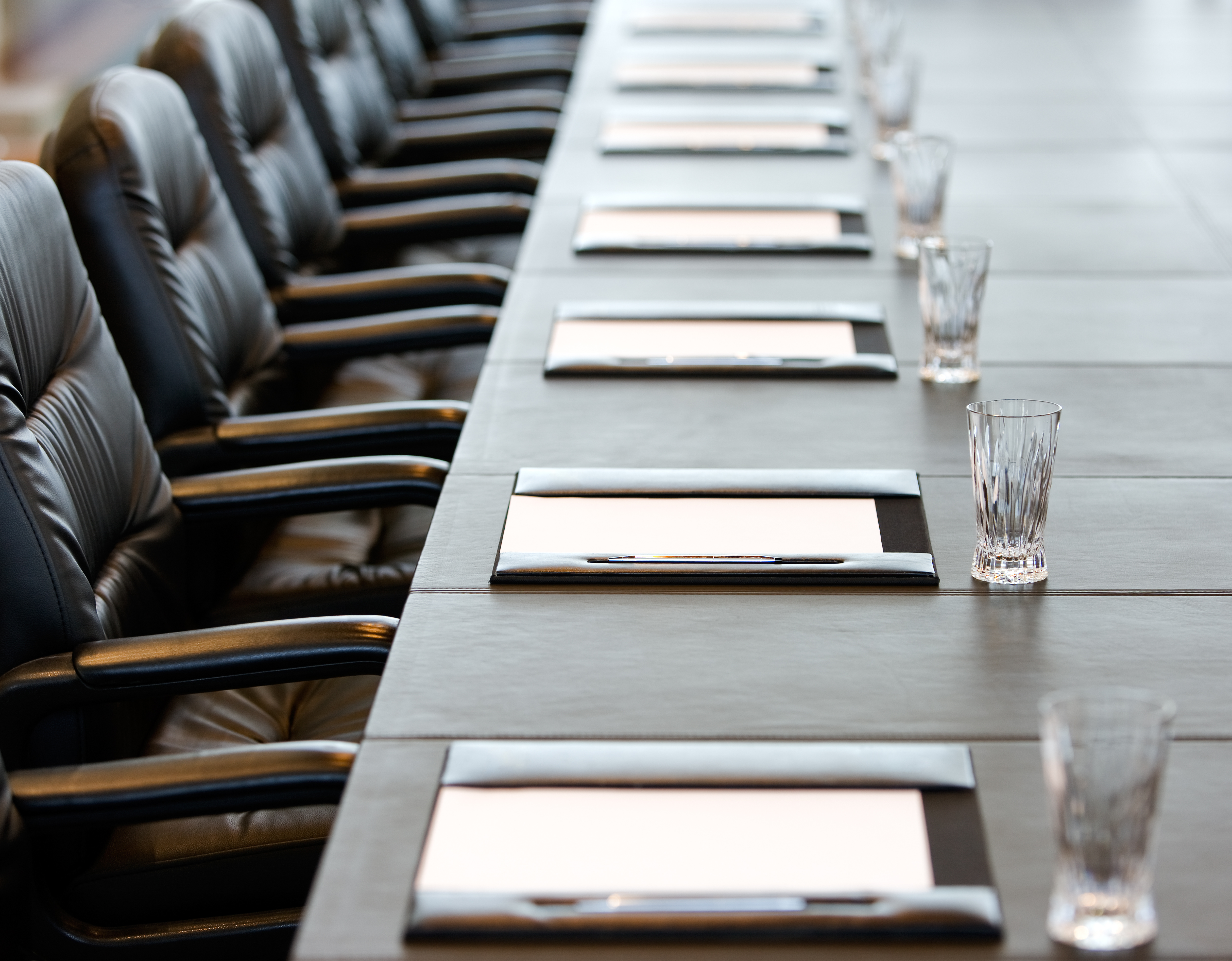 boardroom table with neatly placed papers and water glasses