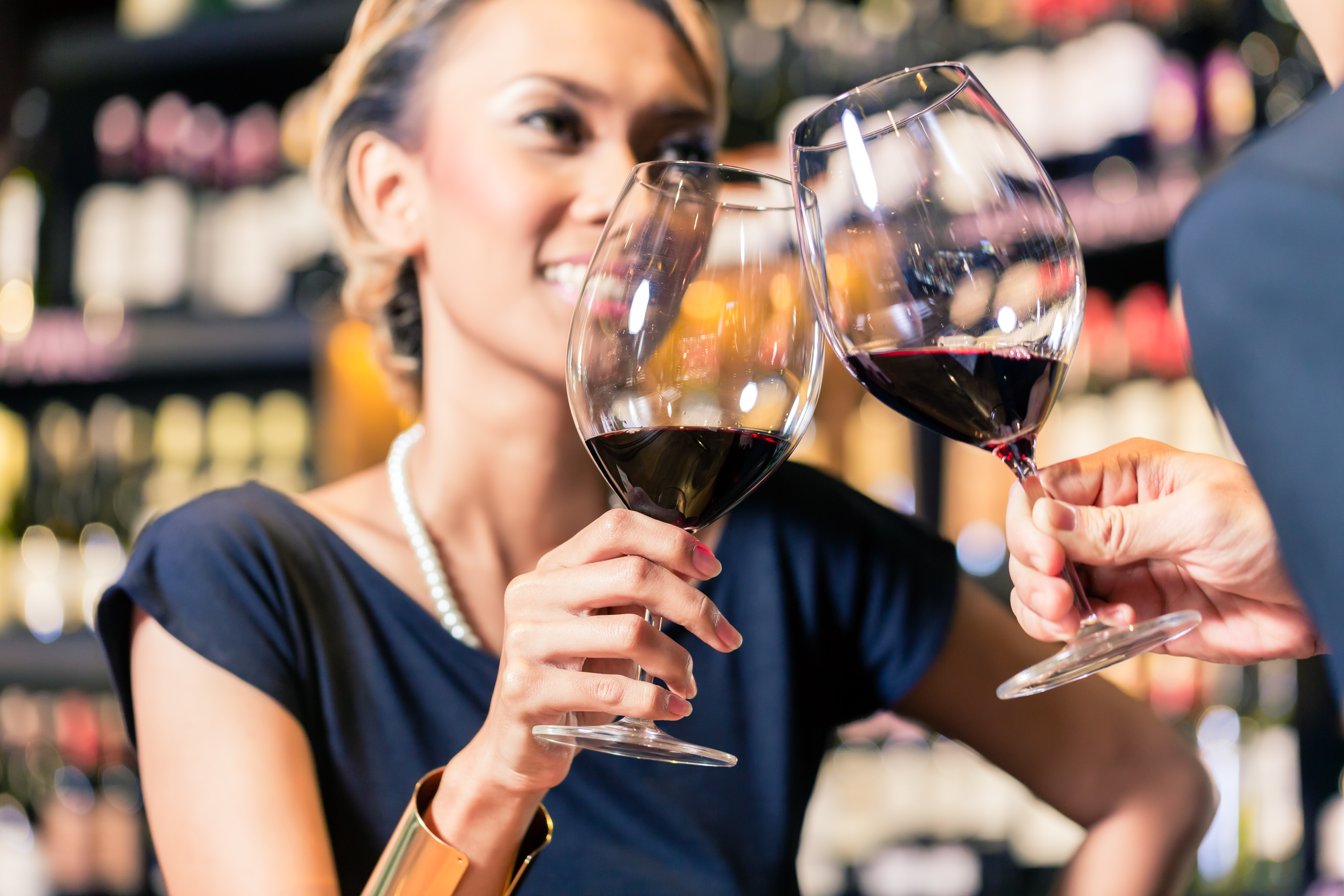 Close up of Asian couple clinking glasses in wine shop