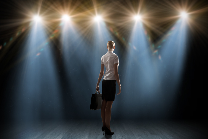 Business woman on stage spotlights holding a briefcase
