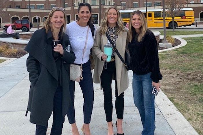 four women in front of a school